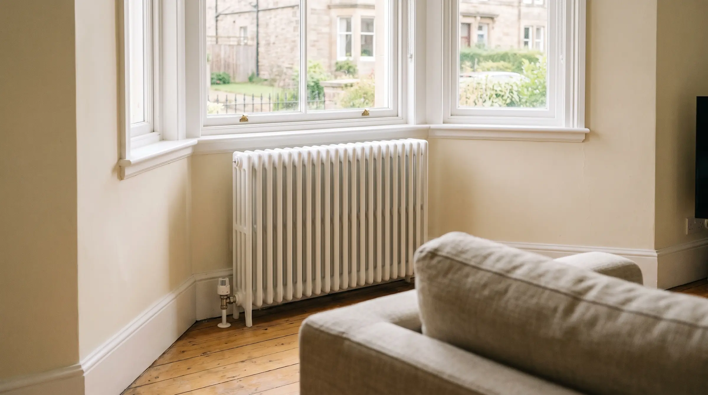 A column radiator under the window of a bright sandstone living room